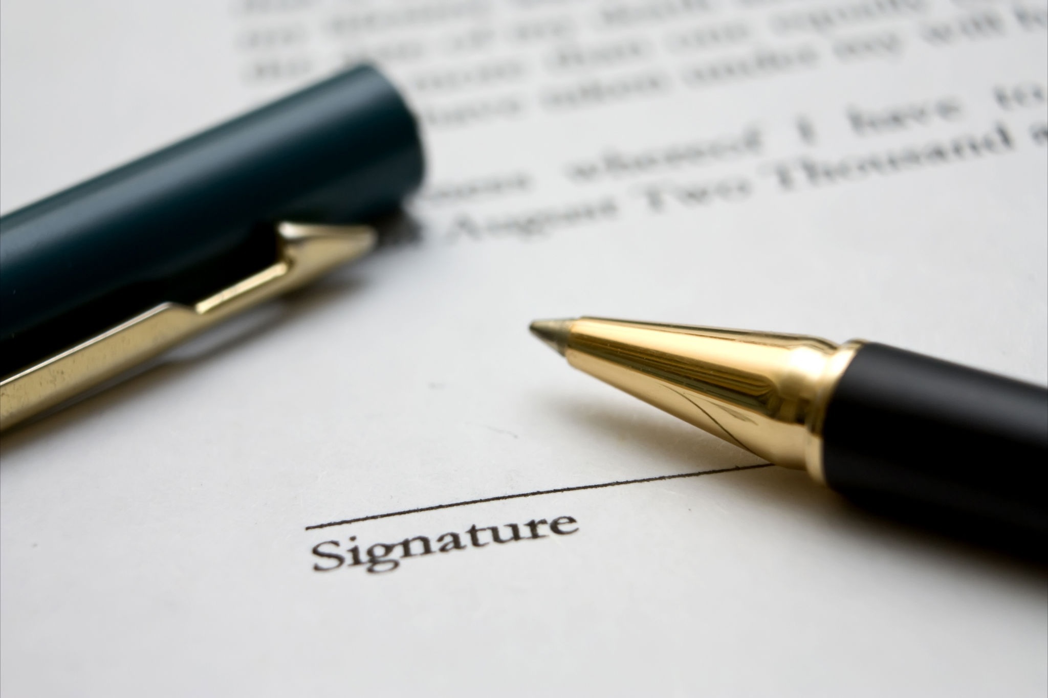 A black and gold pen sits on top of a document near the signature line